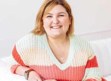 Matisse sits on a white sofa smiling at the camera.