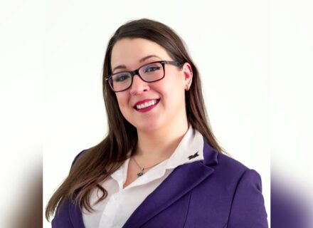 Lauren is a young woman with long brown hair. She is wearing glasses and smiling into the camera.