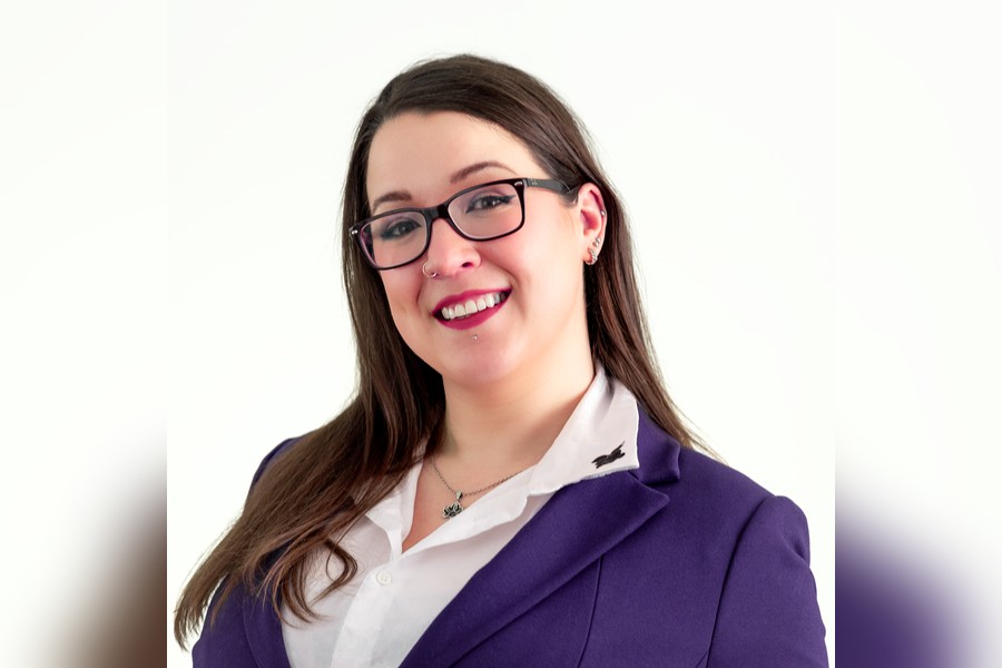Lauren is a young woman with long brown hair. She is wearing glasses and smiling into the camera.